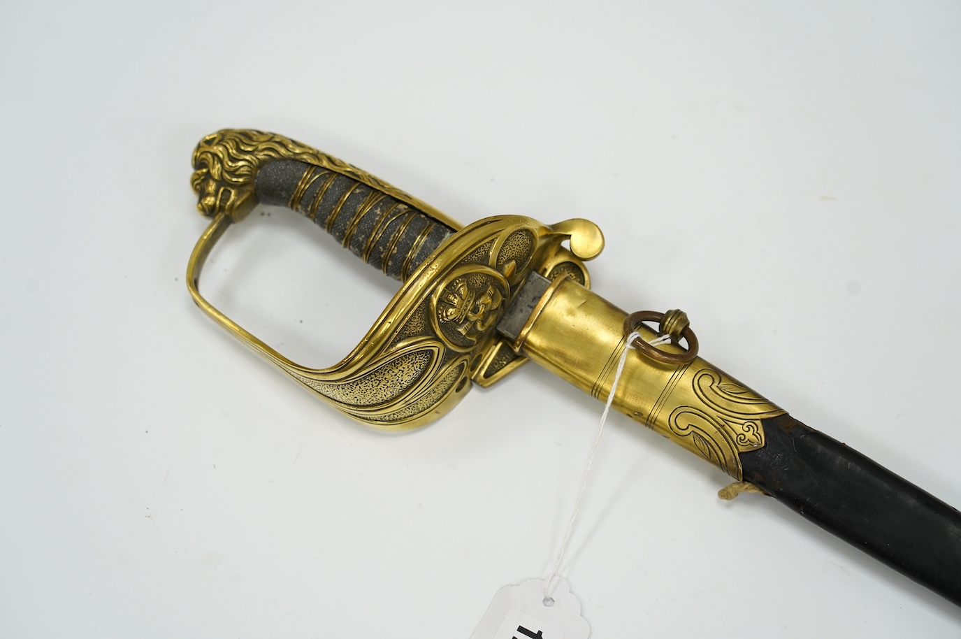 A Victorian warrant officer's sword by Westcott and Sons, regulation brass hilt, black fish skin covered grip, in its brass mounted leather scabbard, blade 79.5cm. Condition - well worn